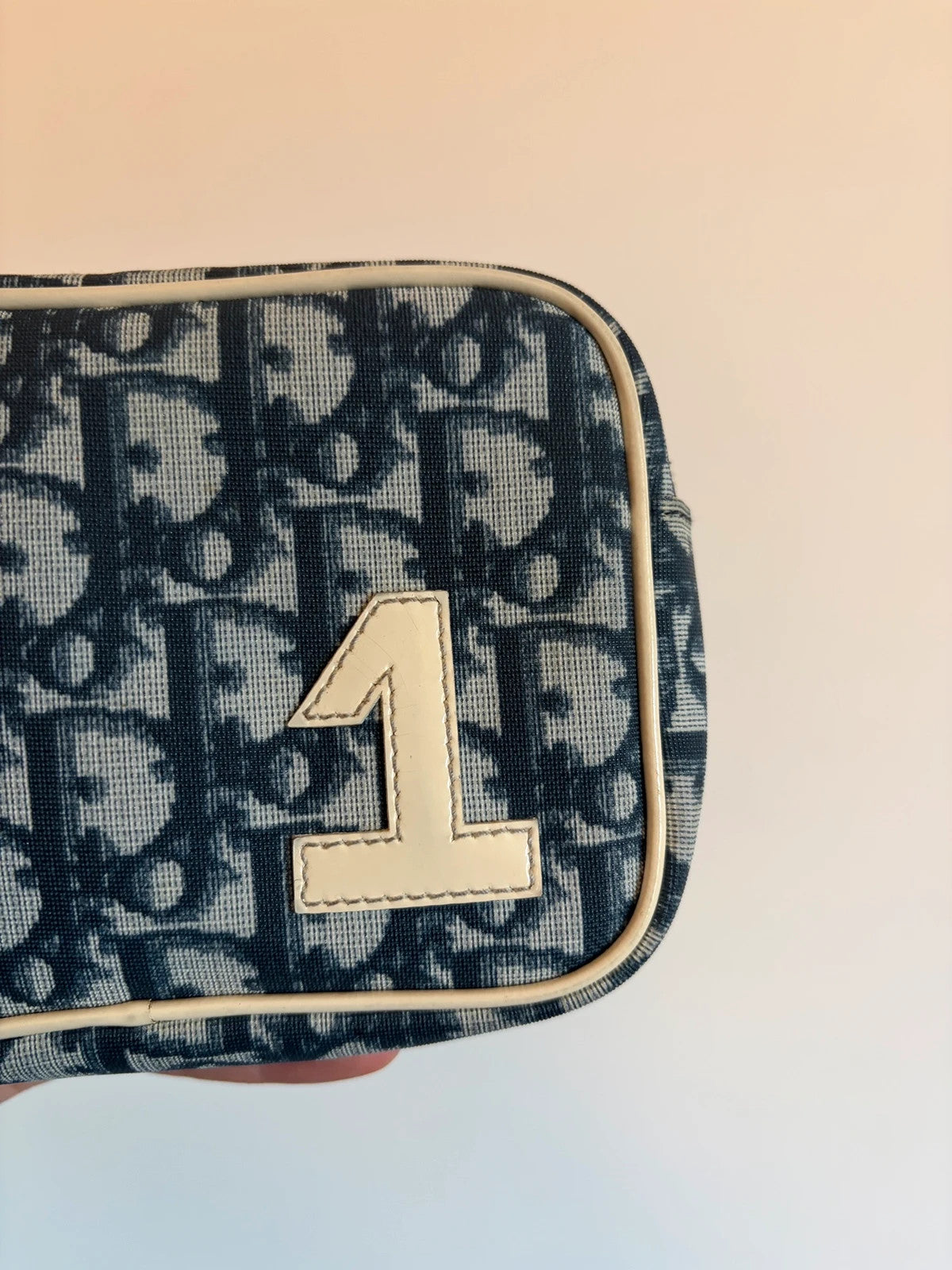 Dior cream and navy wristlet with Trotter monogram, patent leather appliqués, and silver zipper.