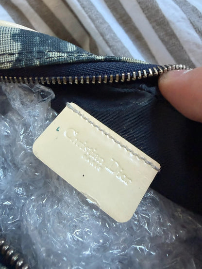 Dior cream and navy wristlet with Trotter monogram, patent leather appliqués, and silver zipper.