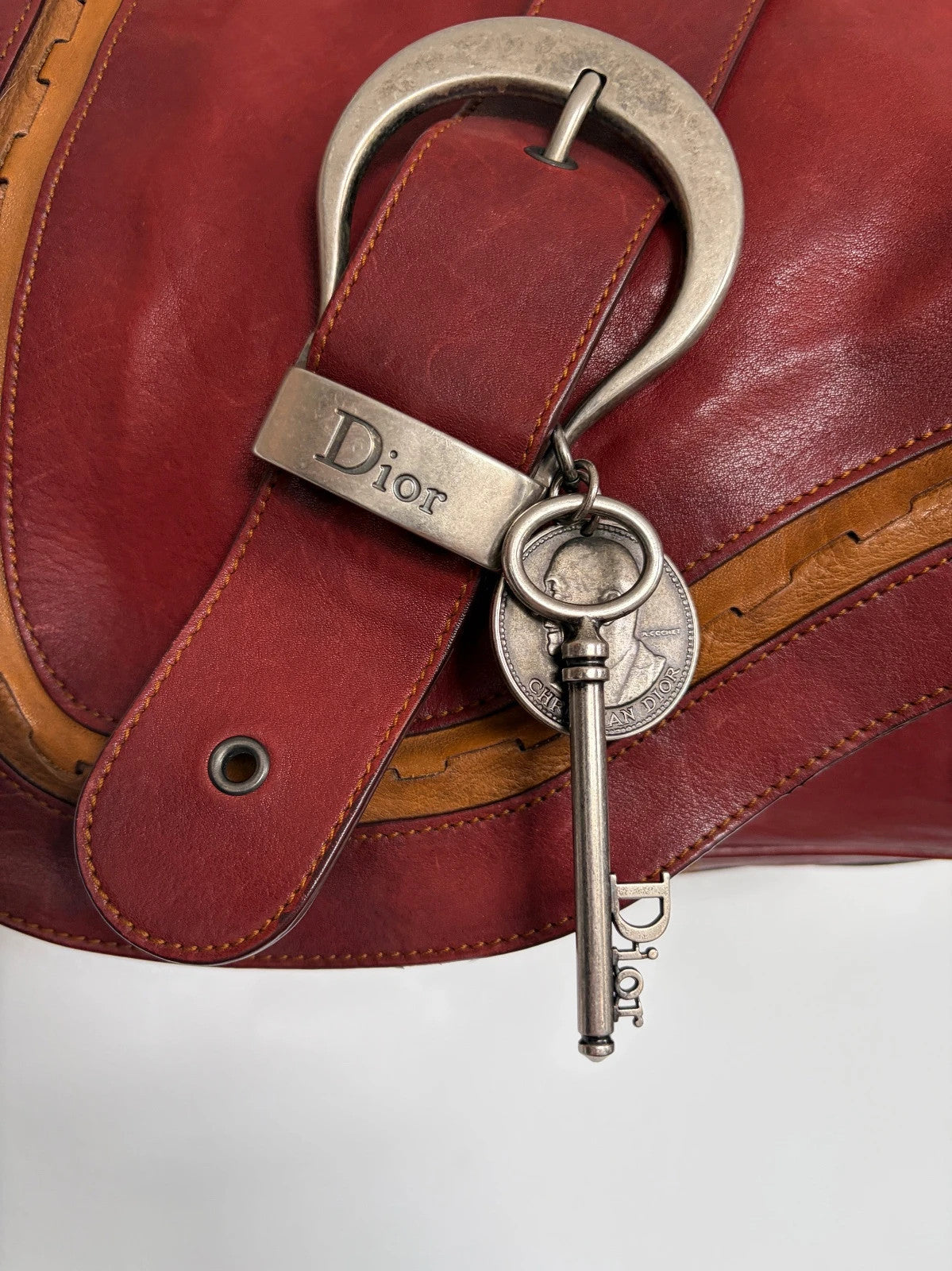 Christian Dior burgundy shoulder bag distressed calfskin leather with tan whipstitch and logo charms.