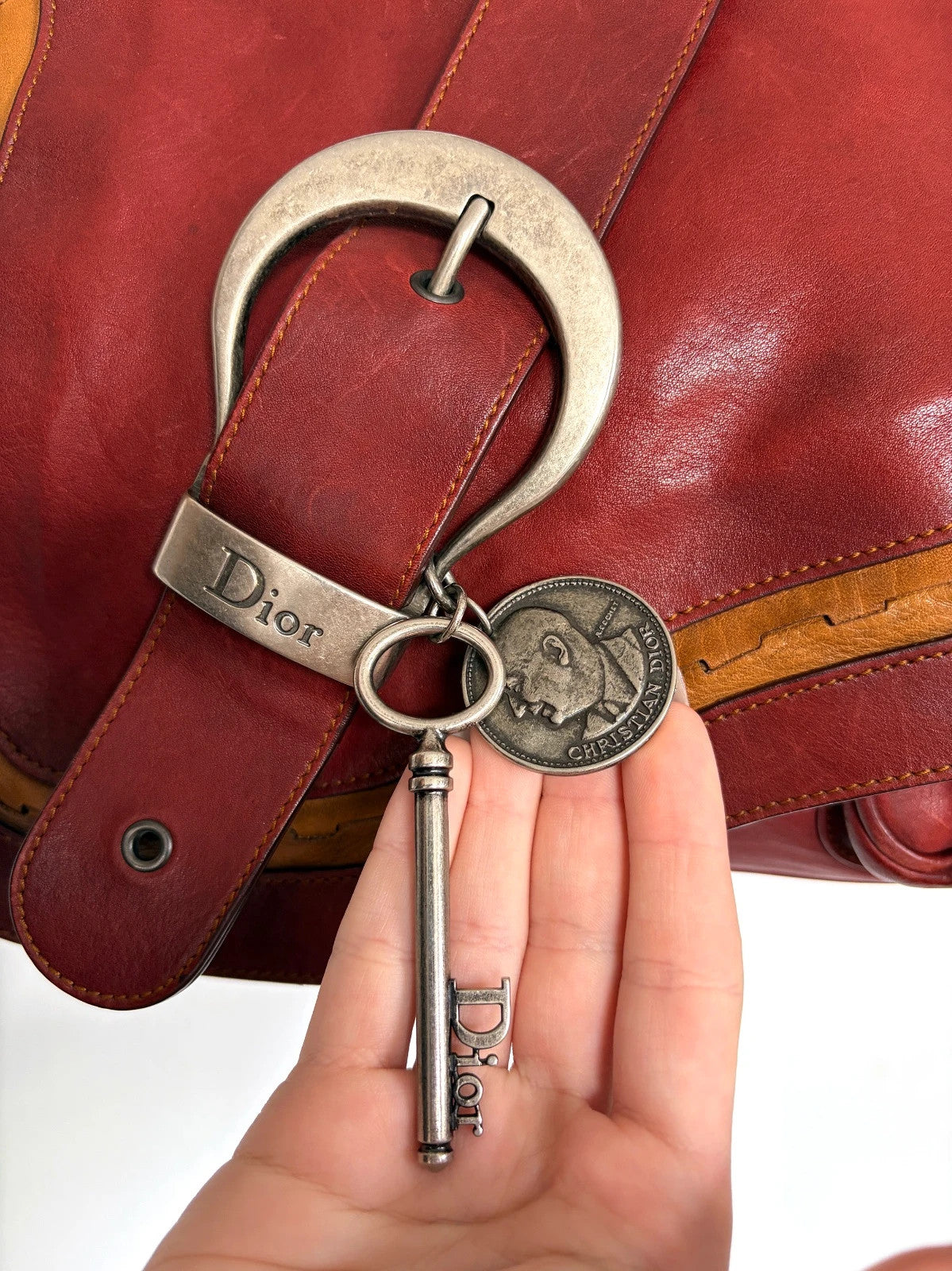 Christian Dior burgundy shoulder bag distressed calfskin leather with tan whipstitch and logo charms.