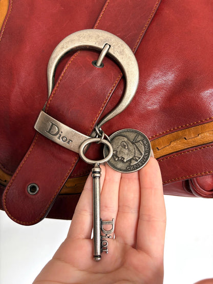 Christian Dior burgundy shoulder bag distressed calfskin leather with tan whipstitch and logo charms.
