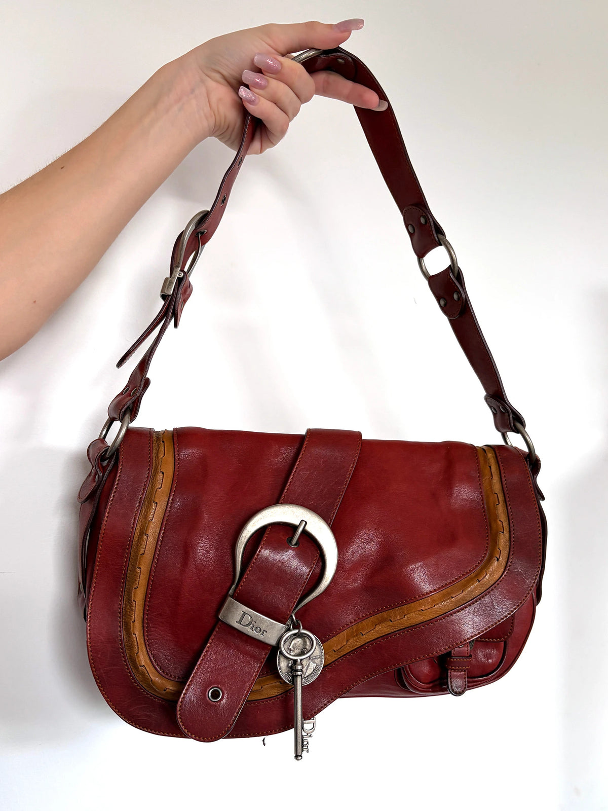 Christian Dior burgundy shoulder bag distressed calfskin leather with tan whipstitch and logo charms.
