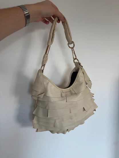 Yves Saint Laurent cream leather hobo bag with tiered ruffles and gold-tone logo plaque.