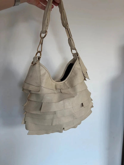 Yves Saint Laurent cream leather hobo bag with tiered ruffles and gold-tone logo plaque.