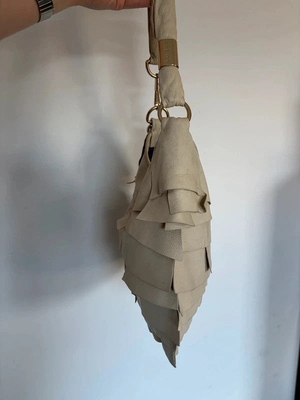 Yves Saint Laurent cream leather hobo bag with tiered ruffles and gold-tone logo plaque.
