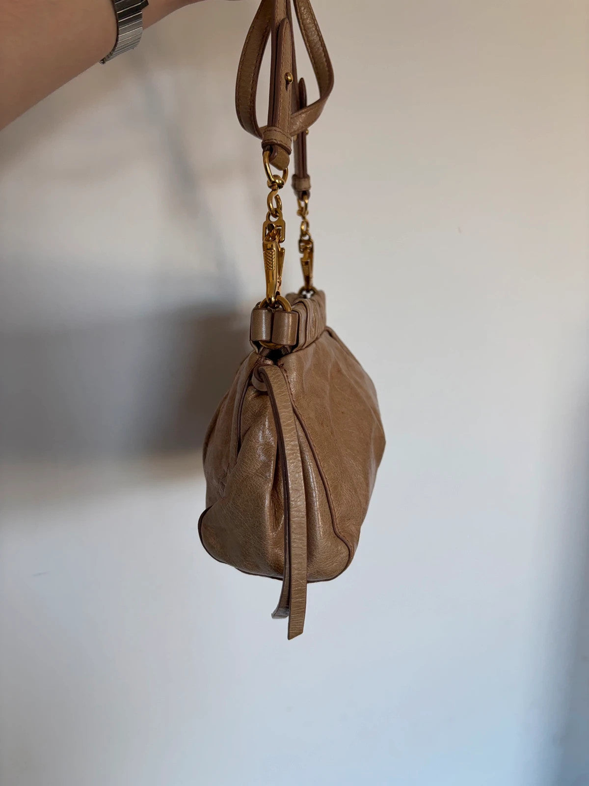 Miu Miu taupe mini crossbody bag with ruched collar, gold lettering, and leather strap.