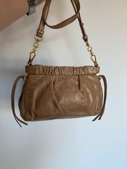 Miu Miu taupe mini crossbody bag with ruched collar, gold lettering, and leather strap.