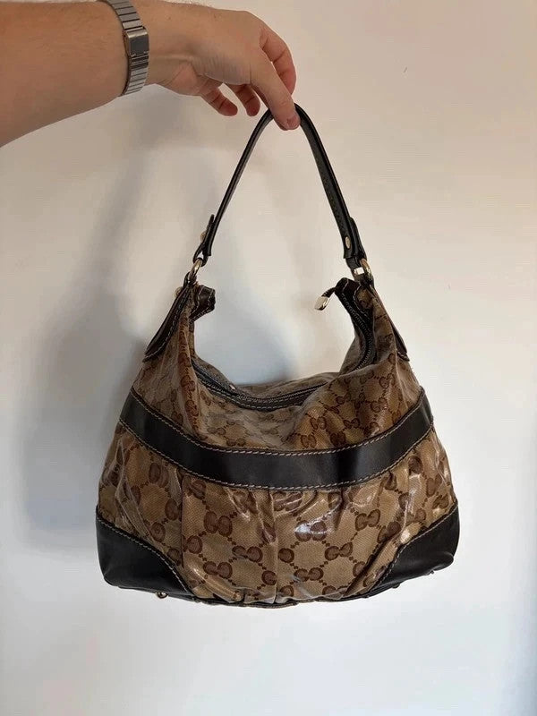 Gucci beige hobo bag with GG crystal monogram, dark brown leather trim, and gold-tone studs.