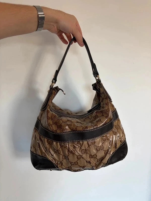 Gucci beige hobo bag with GG crystal monogram, dark brown leather trim, and gold-tone studs.