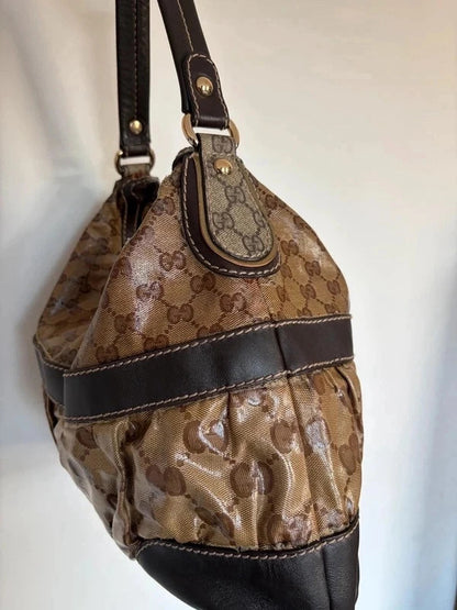 Gucci beige hobo bag with GG crystal monogram, dark brown leather trim, and gold-tone studs.