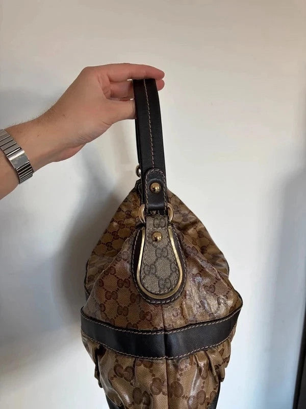 Gucci beige hobo bag with GG crystal monogram, dark brown leather trim, and gold-tone studs.