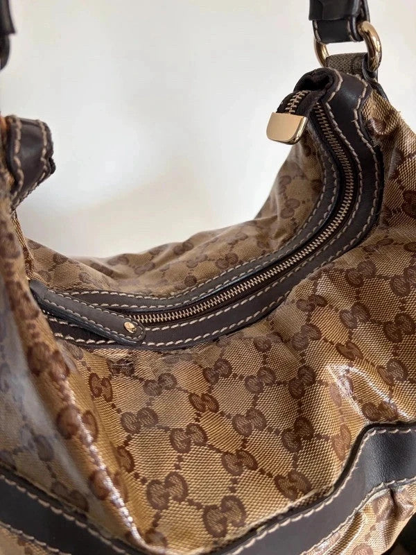 Gucci beige hobo bag with GG crystal monogram, dark brown leather trim, and gold-tone studs.