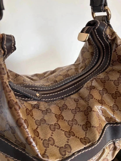 Gucci beige hobo bag with GG crystal monogram, dark brown leather trim, and gold-tone studs.