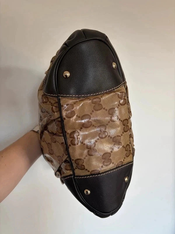 Gucci beige hobo bag with GG crystal monogram, dark brown leather trim, and gold-tone studs.