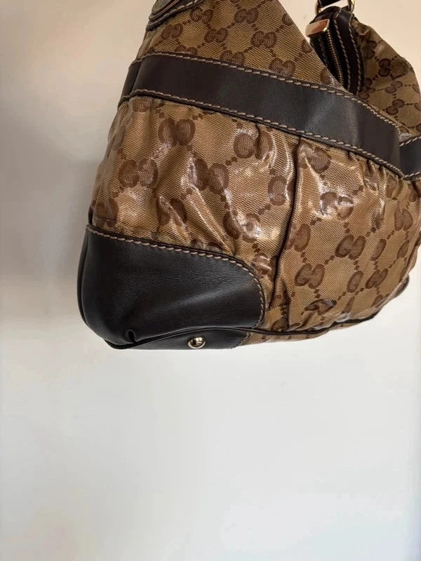 Gucci beige hobo bag with GG crystal monogram, dark brown leather trim, and gold-tone studs.
