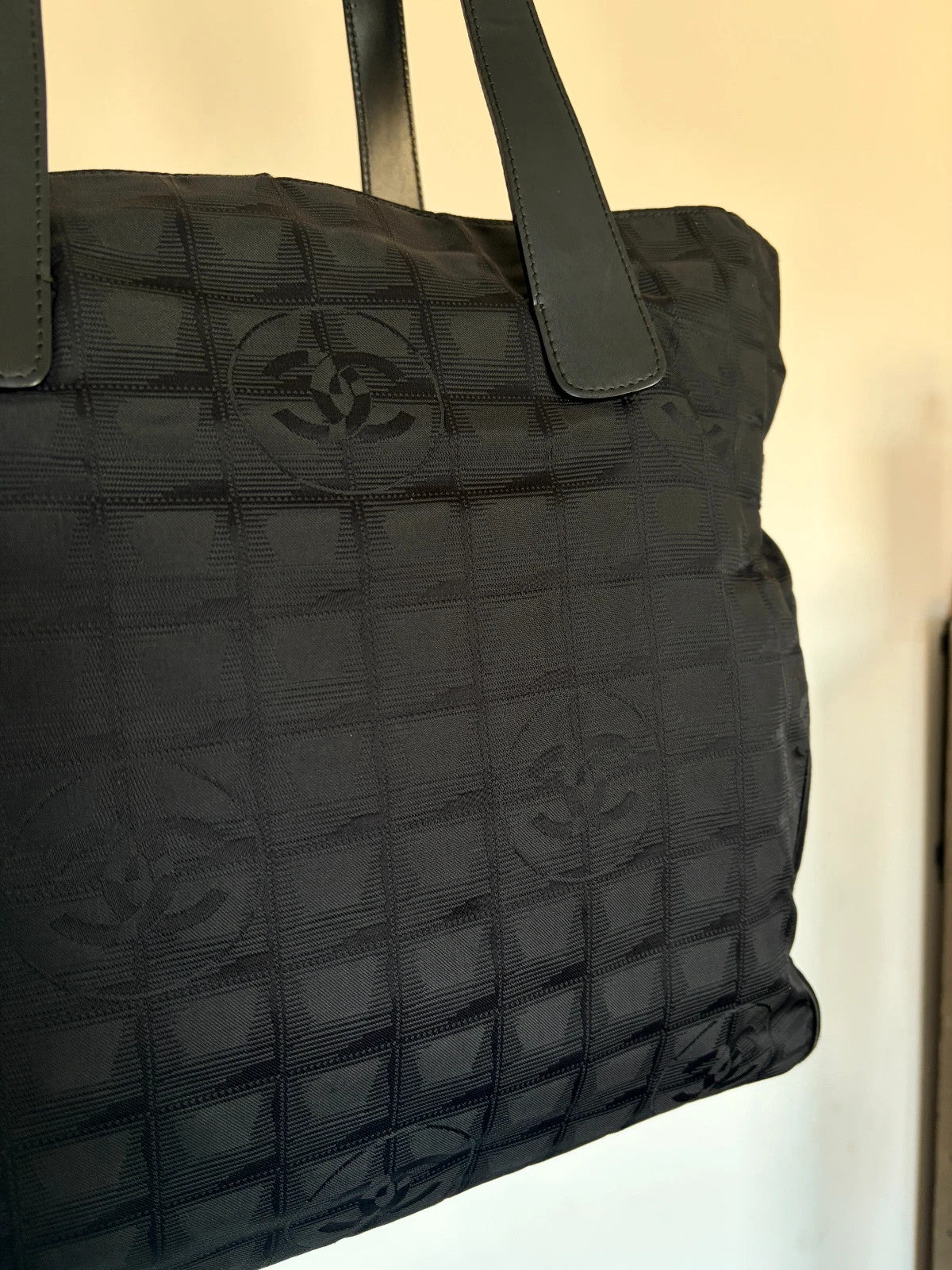 Chanel black shopping tote with CC jacquard pattern and leather shoulder handles.