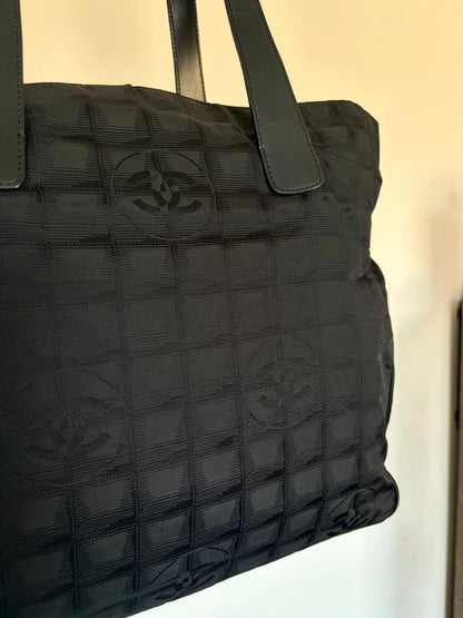 Chanel black shopping tote with CC jacquard pattern and leather shoulder handles.