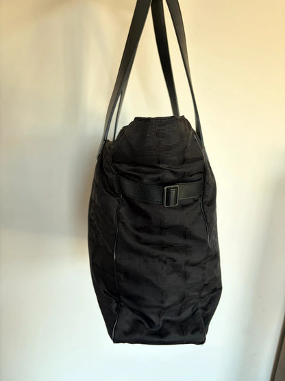 Chanel black shopping tote with woven CC jacquard pattern and smooth calfskin handles.