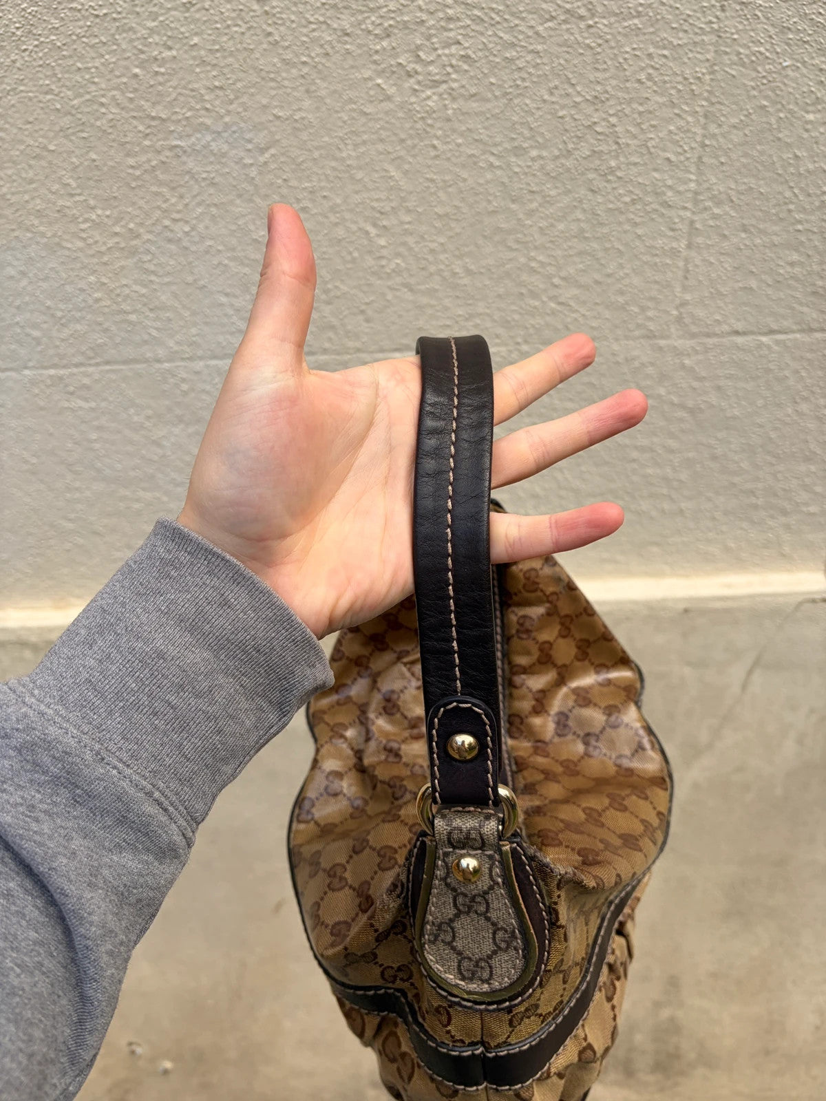 Gucci beige hobo bag with GG Crystal canvas, ruched design, and gold-tone hardware.