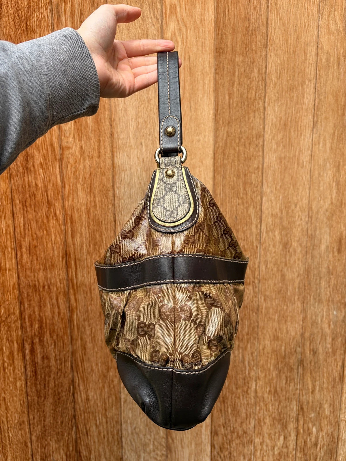 Gucci beige hobo bag with GG Crystal canvas, ruched design, and gold-tone hardware.