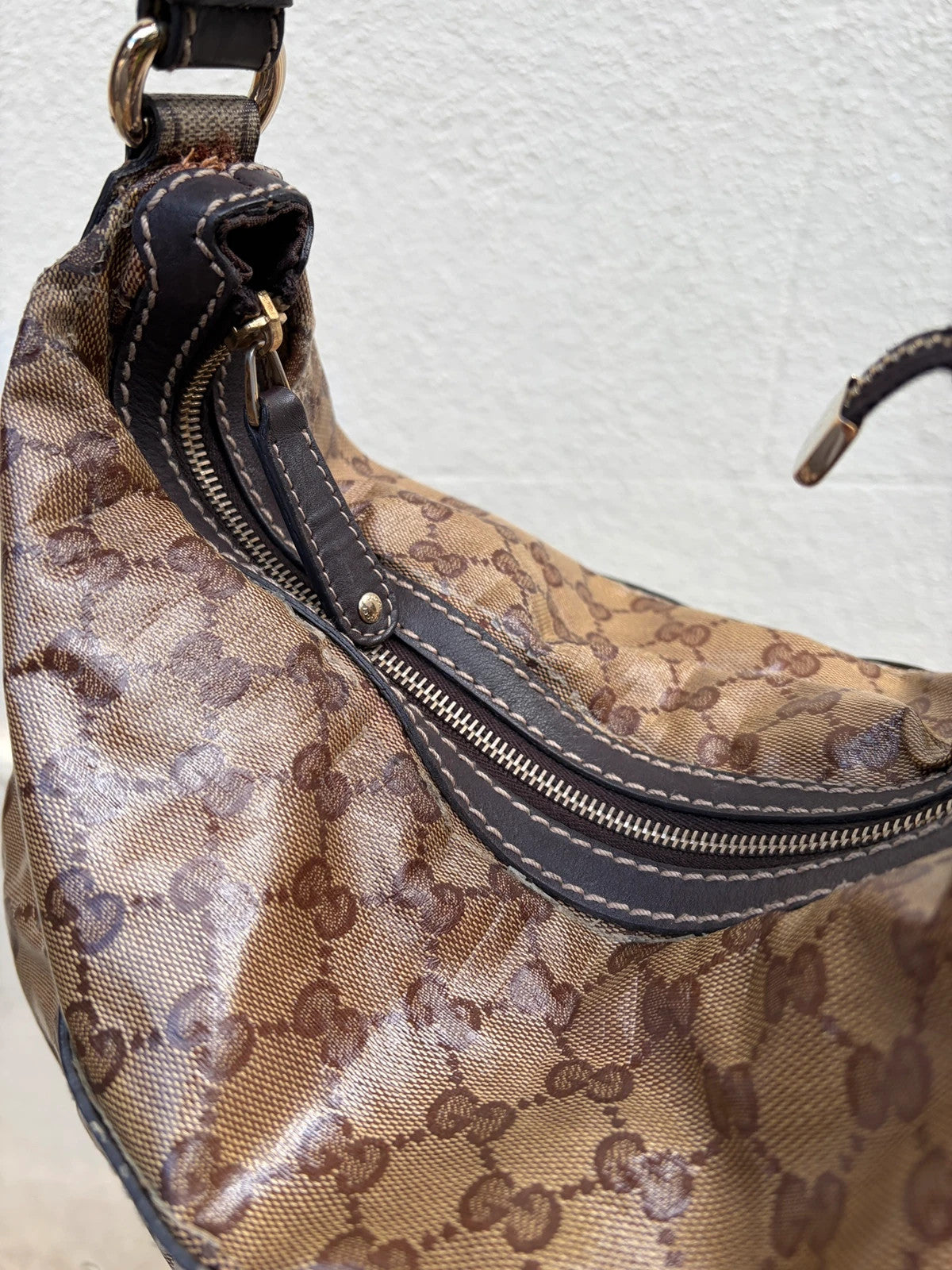 Gucci beige hobo bag with GG Crystal canvas, ruched design, and gold-tone hardware.