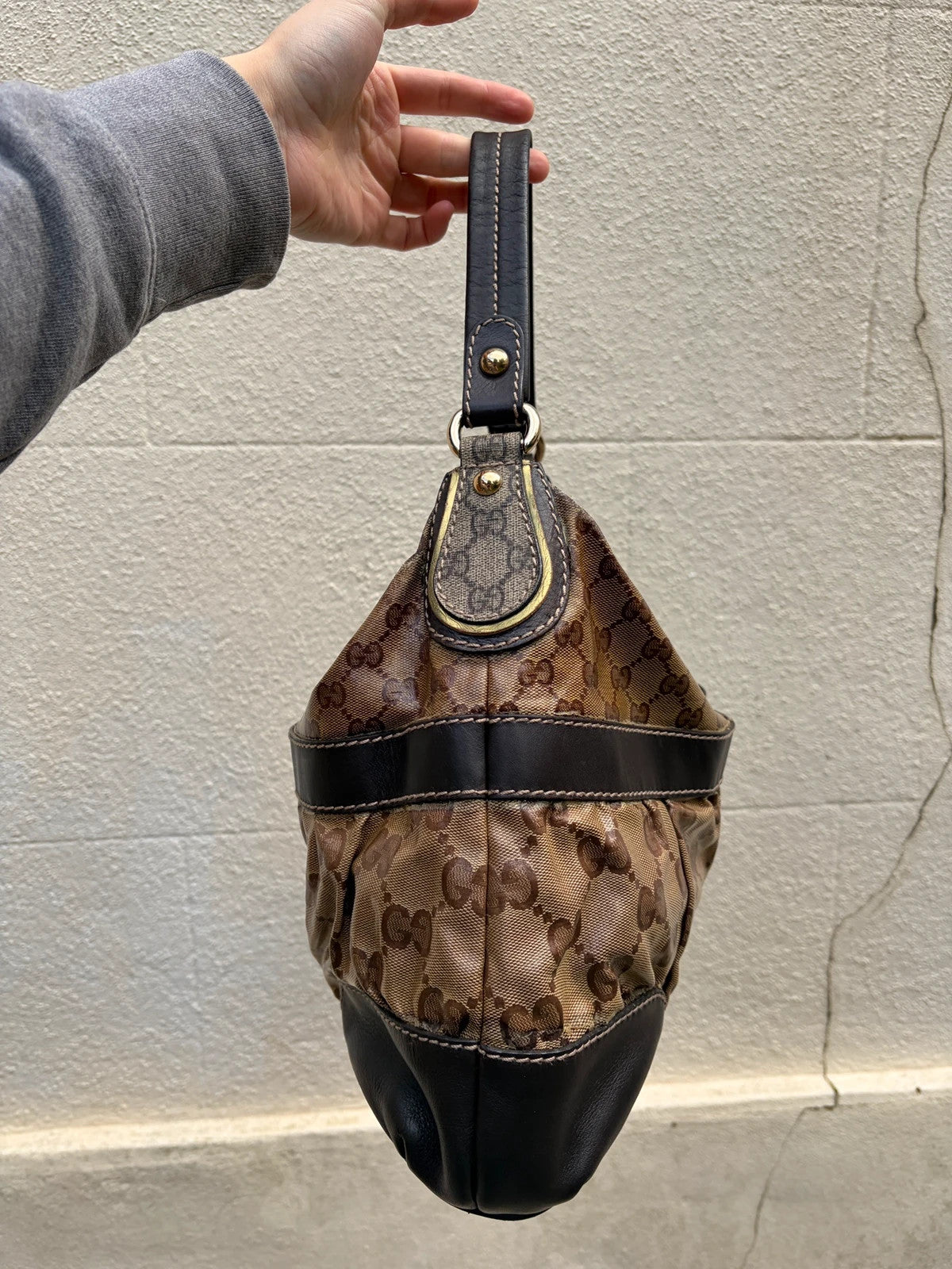 Gucci beige hobo bag with GG Crystal canvas, ruched design, and gold-tone hardware.