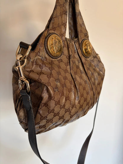 Gucci brown hobo bag with GG monogram, gold-tone knight crest medallions, and leather straps.