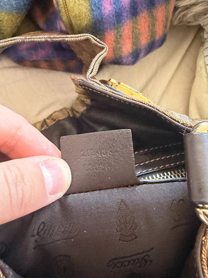 Gucci brown hobo bag with GG monogram, gold-tone knight crest medallions, and leather straps.