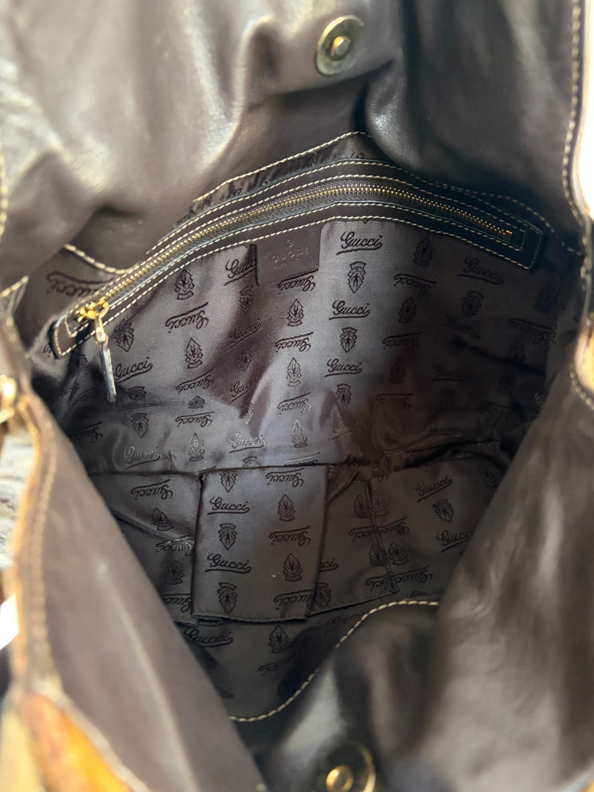 Gucci brown hobo bag with GG monogram, gold-tone knight crest medallions, and leather straps.