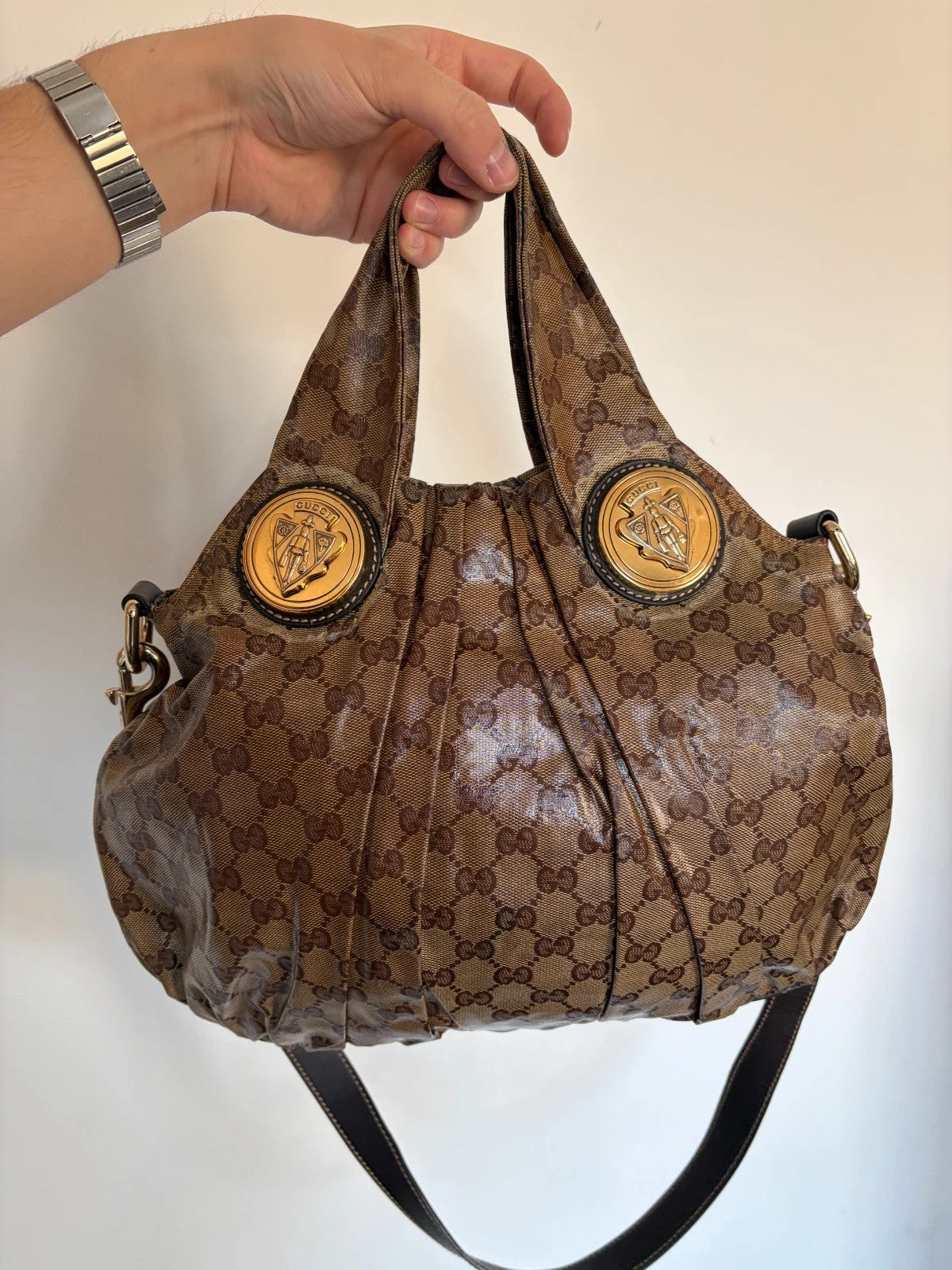 Gucci brown hobo bag with GG monogram, gold-tone knight crest medallions, and leather straps.