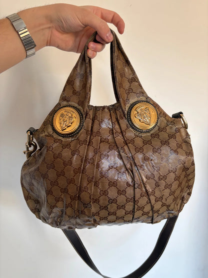 Gucci brown hobo bag with GG monogram, gold-tone knight crest medallions, and leather straps.