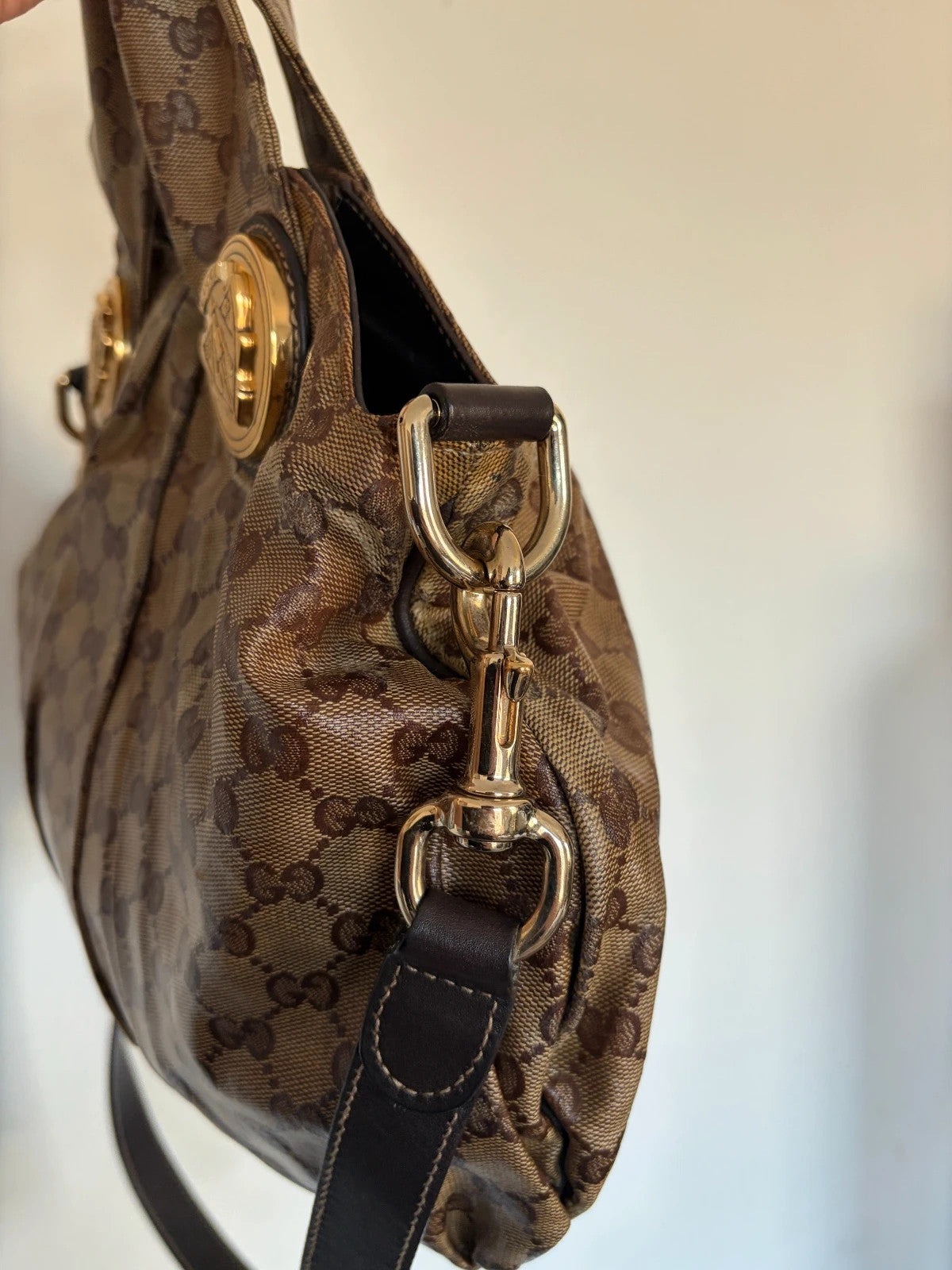 Gucci brown hobo bag with GG monogram, gold-tone knight crest medallions, and leather straps.