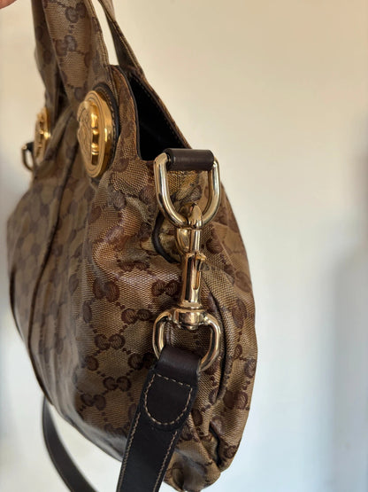 Gucci brown hobo bag with GG monogram, gold-tone knight crest medallions, and leather straps.