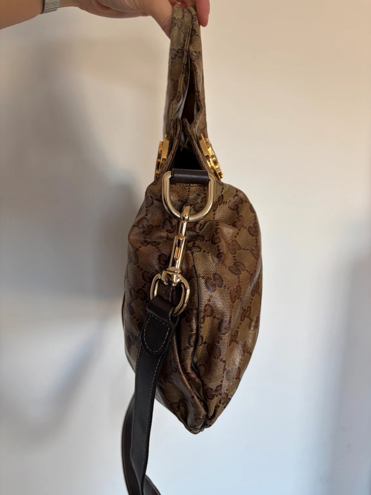 Gucci brown hobo bag with GG monogram, gold-tone knight crest medallions, and leather straps.
