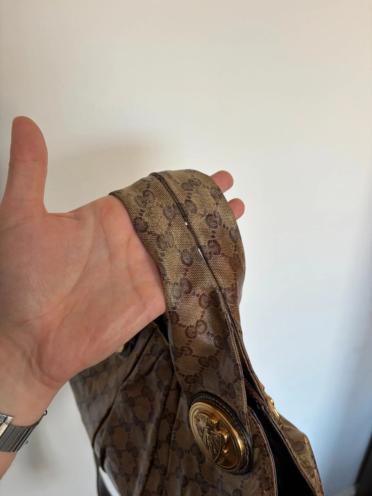 Gucci brown hobo bag with GG monogram, gold-tone knight crest medallions, and leather straps.