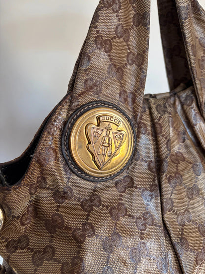Gucci brown hobo bag with GG monogram, gold-tone knight crest medallions, and leather straps.
