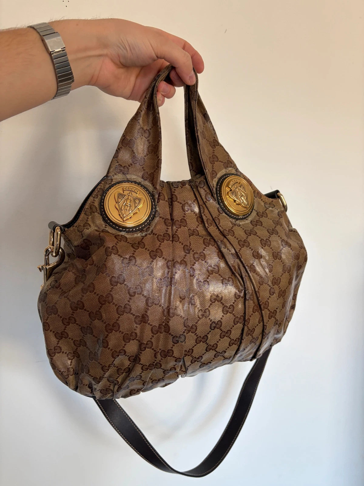 Gucci brown hobo bag with GG monogram, gold-tone knight crest medallions, and leather straps.