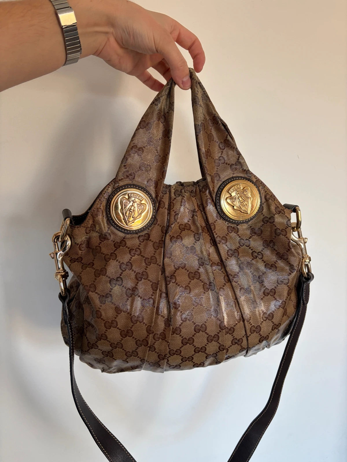 Gucci brown hobo bag with GG monogram, gold-tone knight crest medallions, and leather straps.