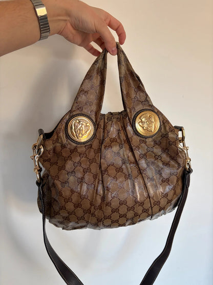Gucci brown hobo bag with GG monogram, gold-tone knight crest medallions, and leather straps.