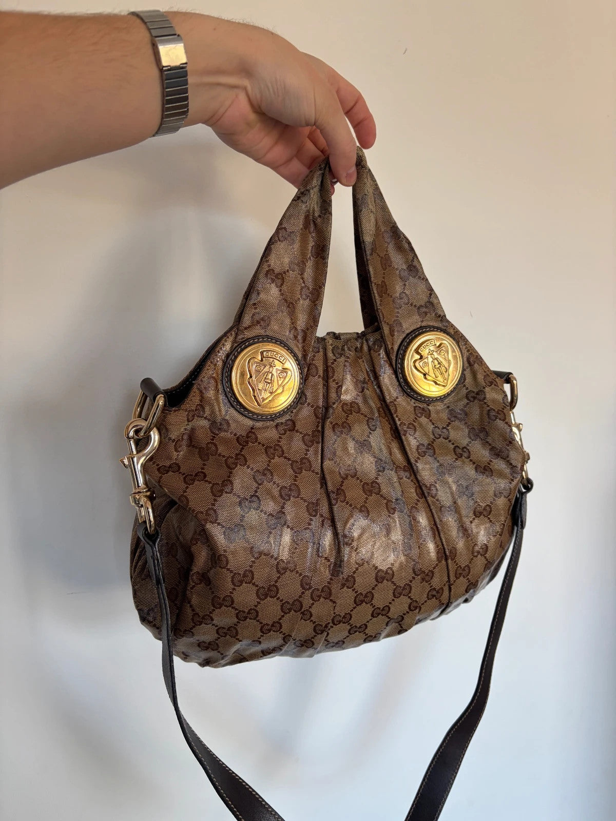 Gucci brown hobo bag with GG monogram, gold-tone knight crest medallions, and leather straps.