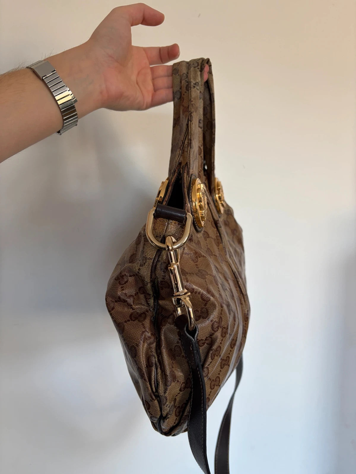 Gucci brown hobo bag with GG monogram, gold-tone knight crest medallions, and leather straps.