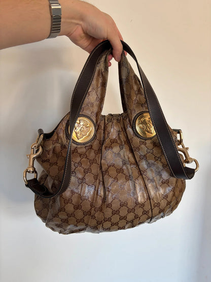 Gucci brown hobo bag with GG monogram, gold-tone knight crest medallions, and leather straps.