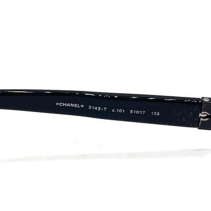 Chanel black rectangular rimless eyeglasses with white CC detailing and adjustable nose pads.