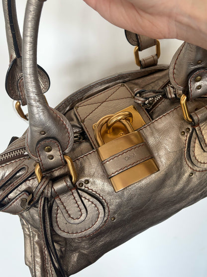 Chloé beige metallic handbag with oversized brass padlock and dual rolled handles.
