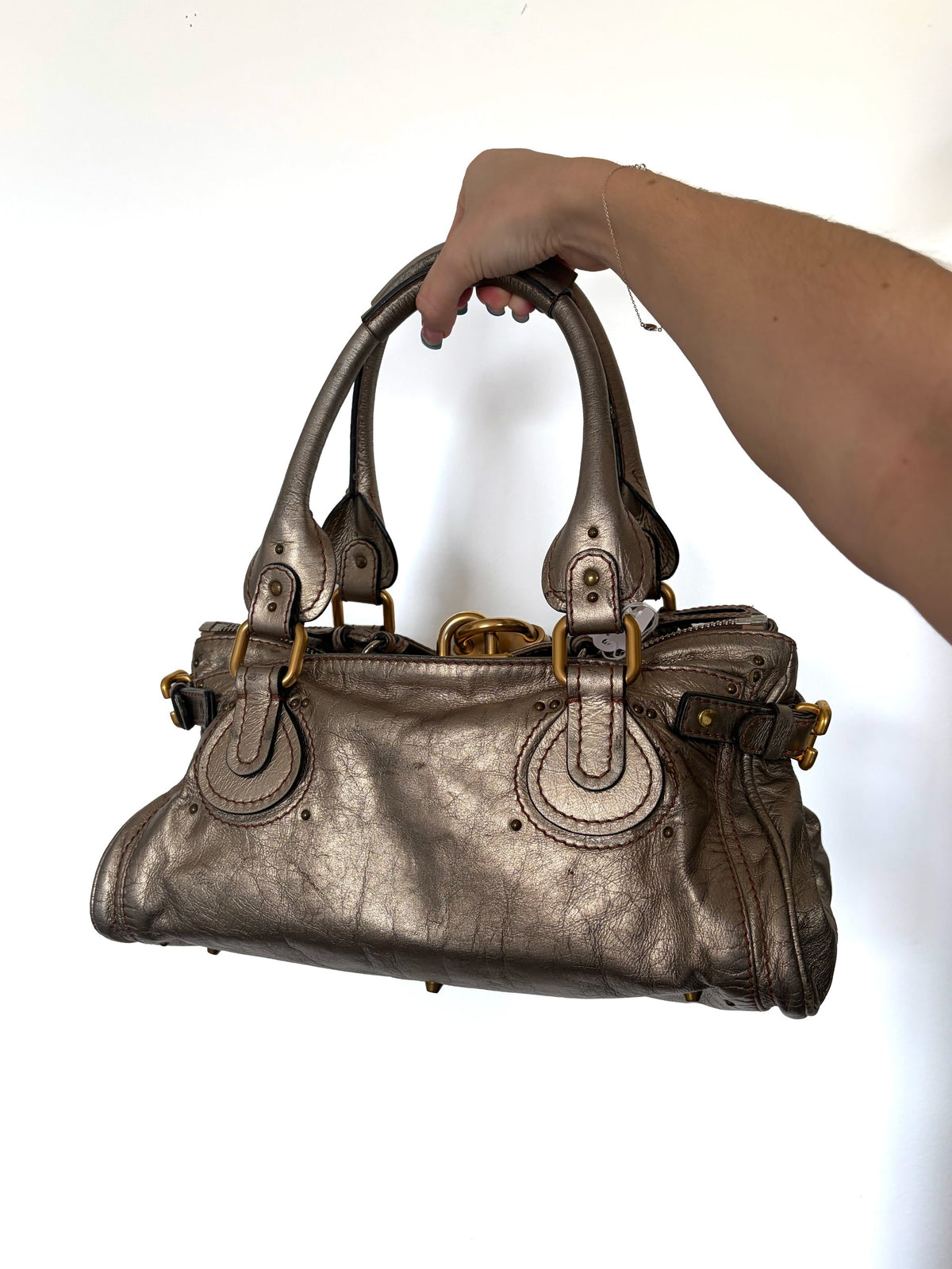 Chloé beige metallic handbag with oversized brass padlock and dual rolled handles.
