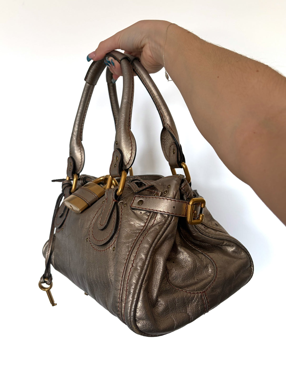 Chloé beige metallic handbag with oversized brass padlock and dual rolled handles.