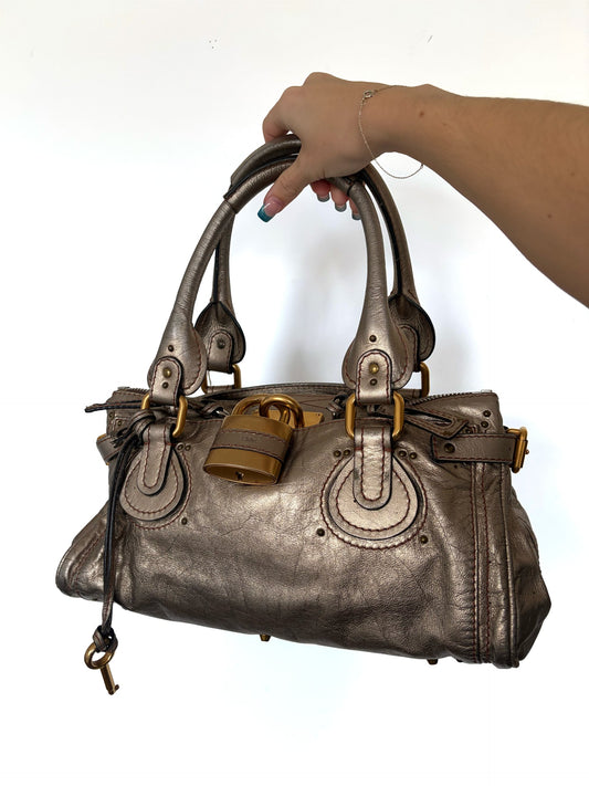 Chloé beige metallic handbag with oversized brass padlock and dual rolled handles.