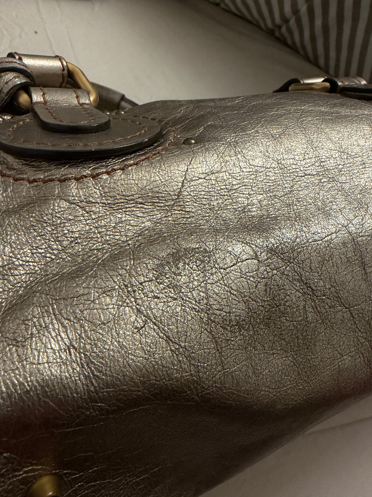 Chloé beige metallic handbag with oversized brass padlock and dual rolled handles.