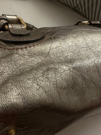 Chloé beige metallic handbag with oversized brass padlock and dual rolled handles.