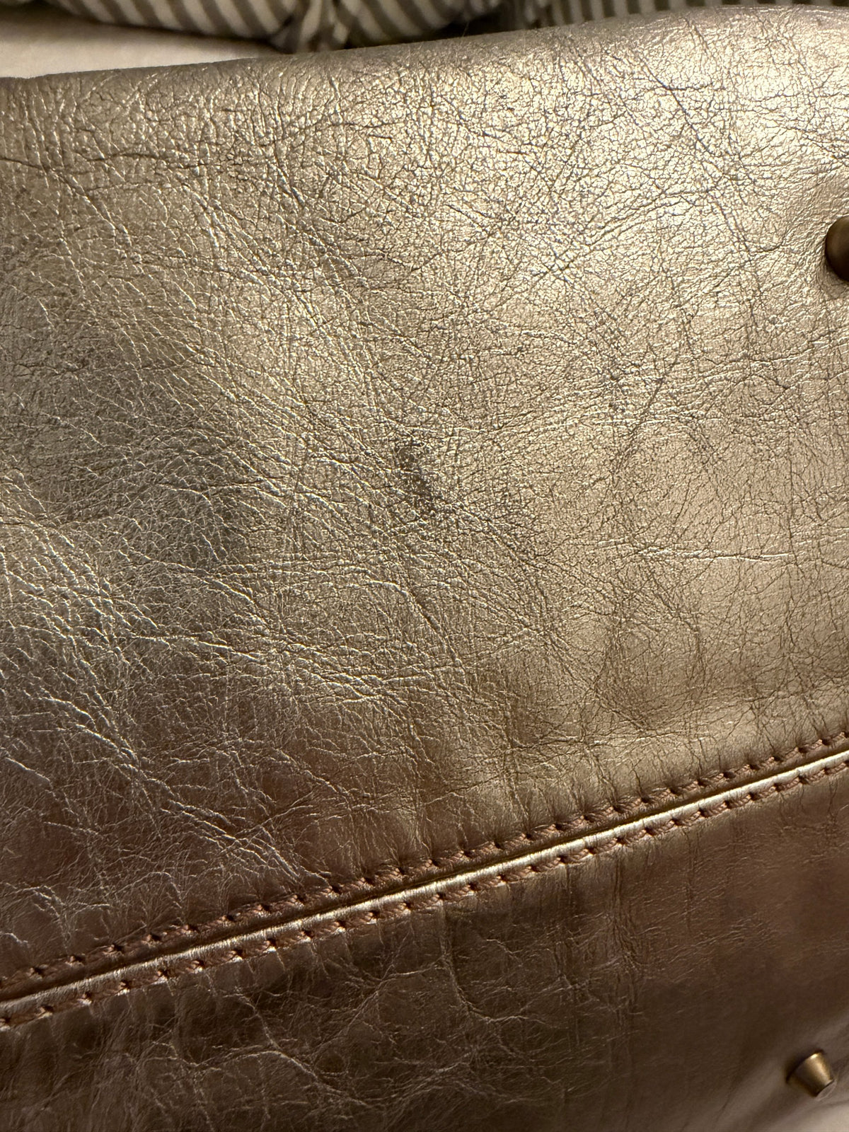 Chloé beige metallic handbag with oversized brass padlock and dual rolled handles.